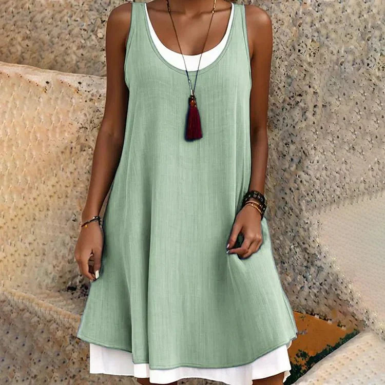 Women's sleeveless mini dress, dark flowy outer layer over white underlayer faux two-piece design