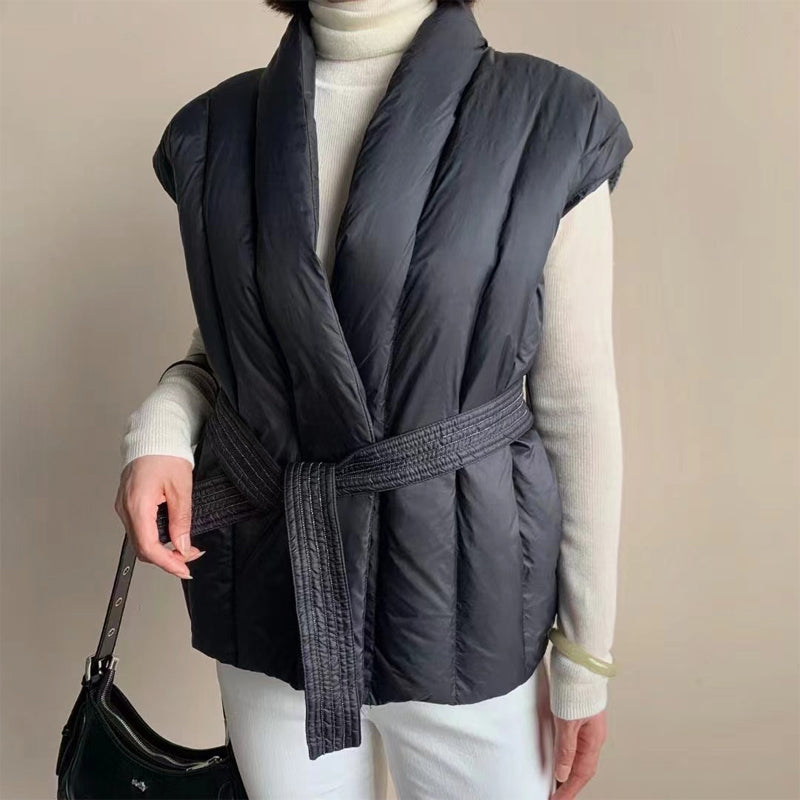 Quilted sleeveless puffer vest in neutral tone with wrap silhouette and textured waist belt