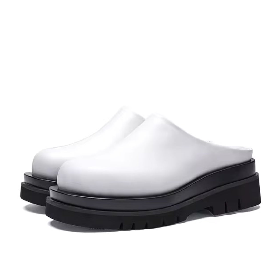 Black leather platform mules with chunky sole and minimalist slip-on silhouette