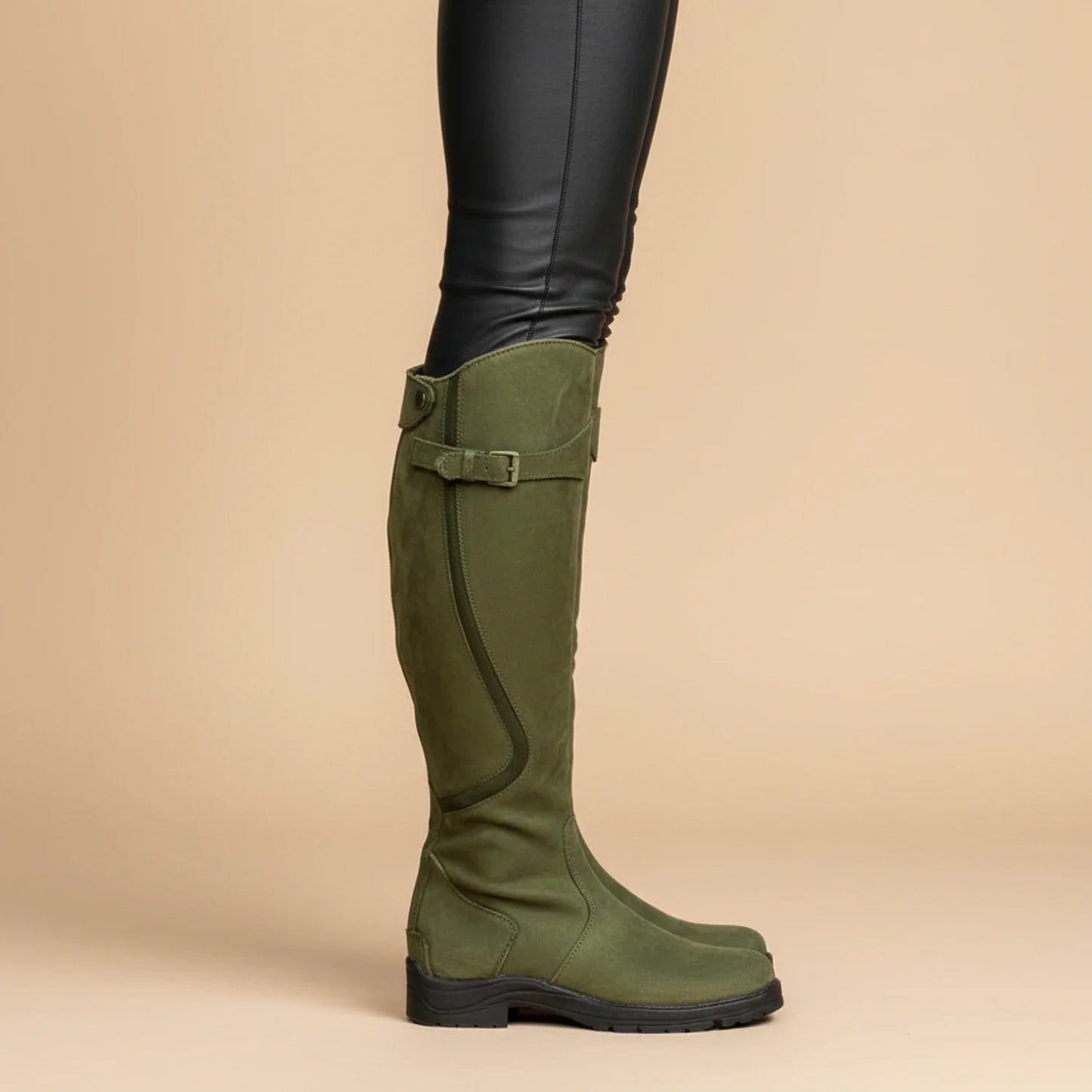 Women's brown leather knee-high riding boots with subtle buckle detail and flat heel