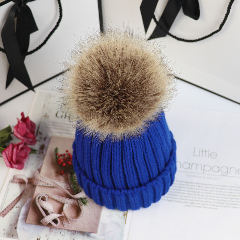 Classic cozy knit beanie in neutral tone with fluffy pom-pom accent for a chic feminine winter look