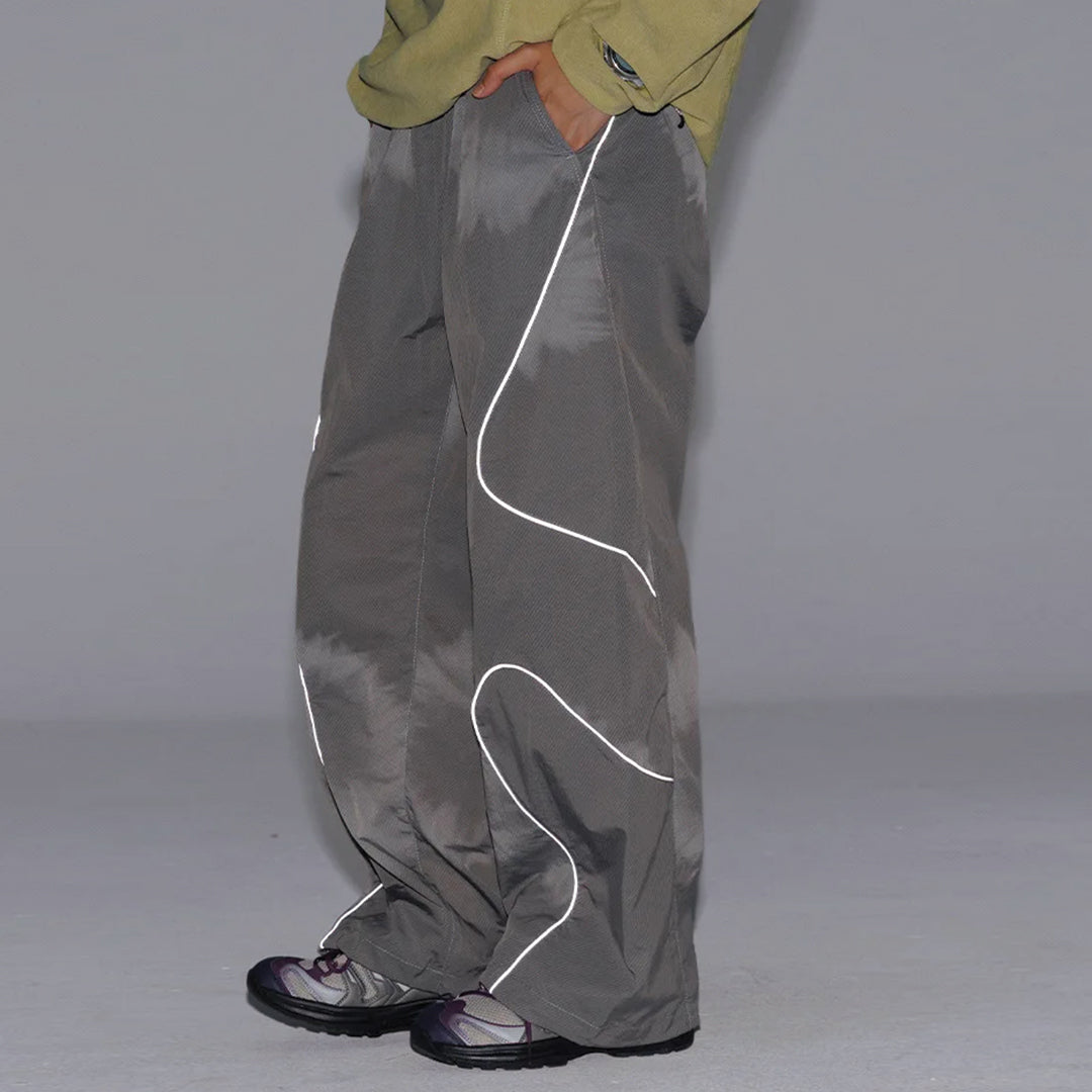 Black wide-leg nylon trousers with curved reflective stripes, drawstring waist, water-resistant
