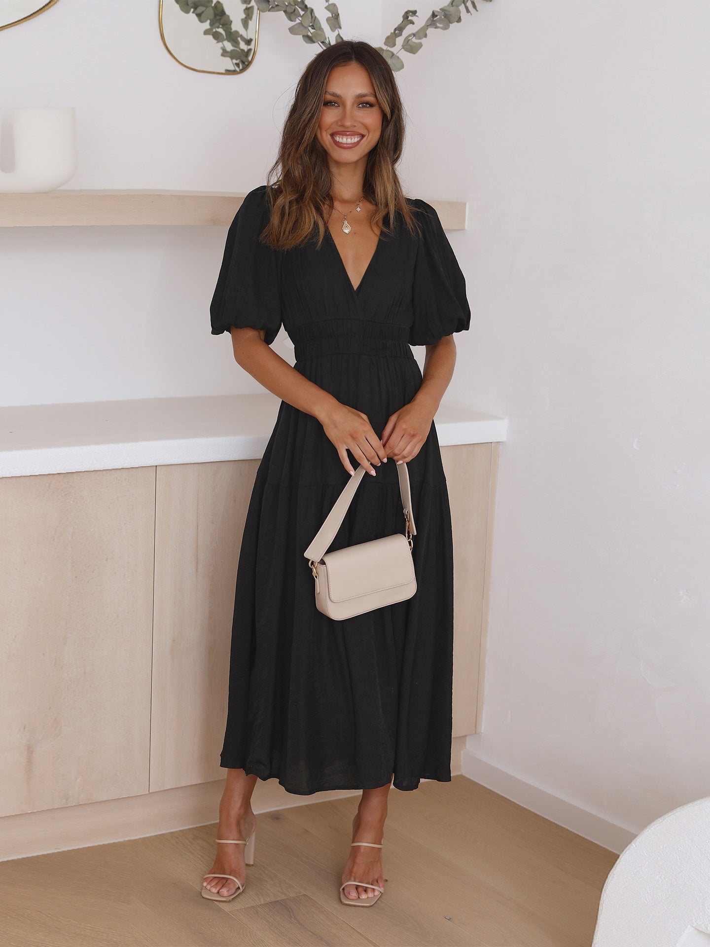 Black women's midi dress with deep V-neck, puff sleeves, and smocked cinched waist flowing skirt
