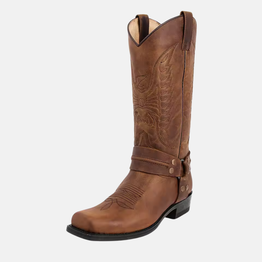 Men's brown leather western boot with embroidered stitching, harness strap, and metal O-ring accent