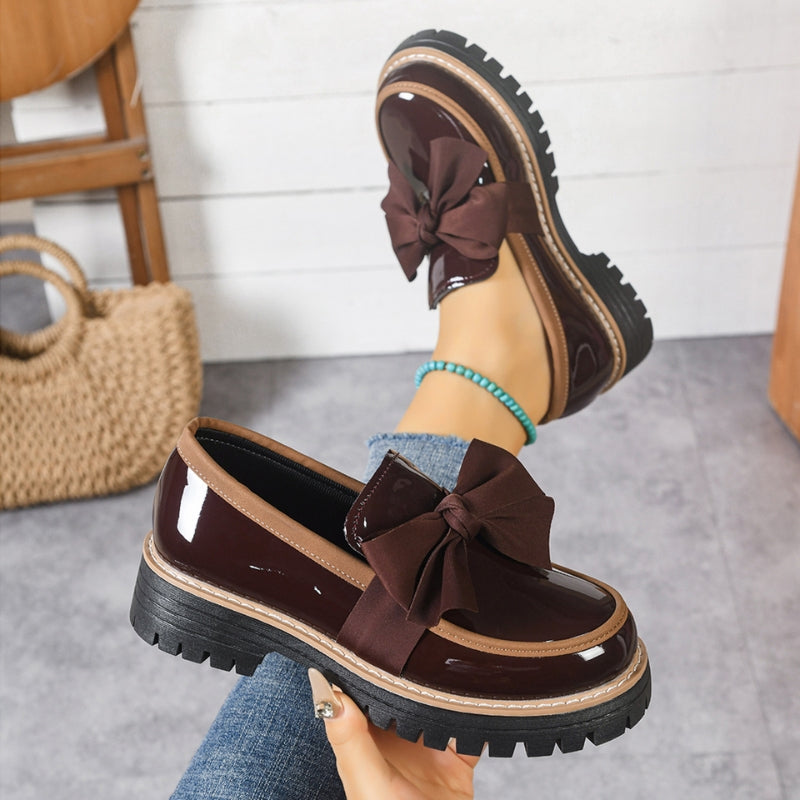 Women's black patent platform loafers with chunky sole and statement bow detail slip-on style