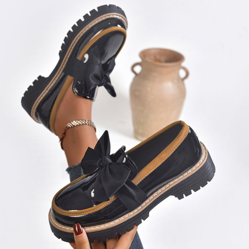 Women's black patent platform loafers with chunky sole and statement bow slip-on detail