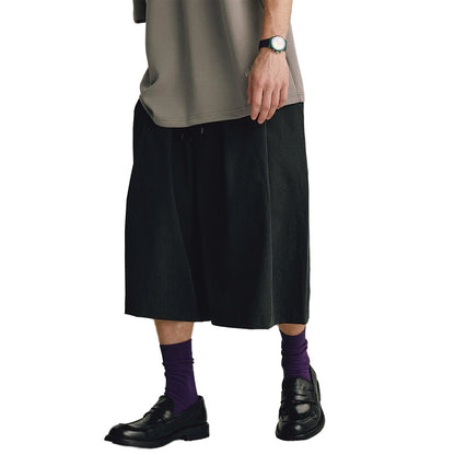 Mono wide-leg pleated shorts in neutral tone with elastic waist and drawstring closure, calf length