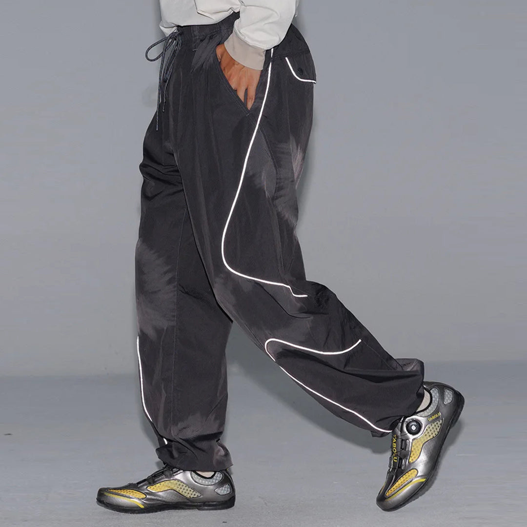 Black wide-leg nylon trousers with curved reflective stripes, drawstring waist, relaxed athletic fit