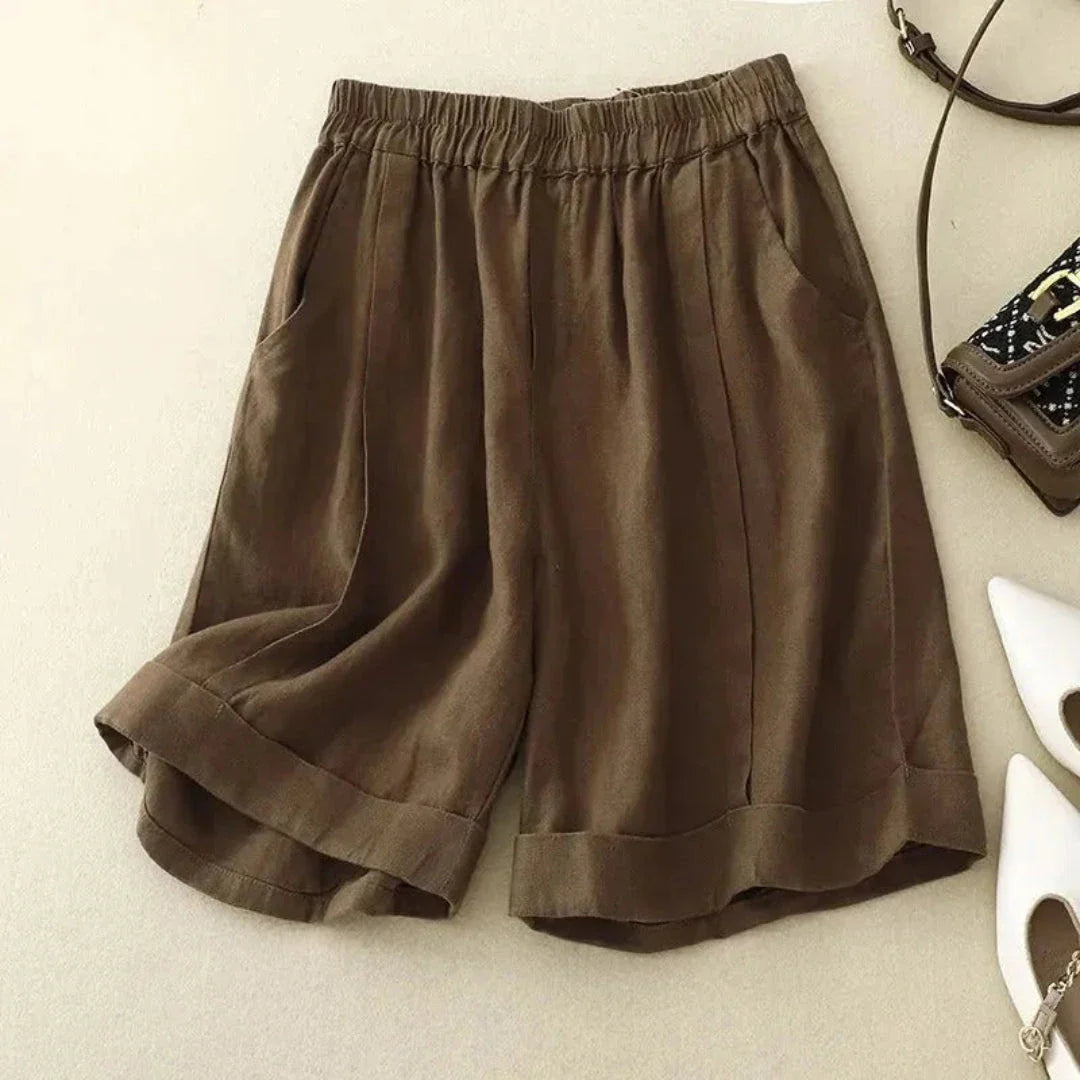 Beige high-rise linen shorts with rolled hem cuffs and elastic waistband for effortless warm-weather style