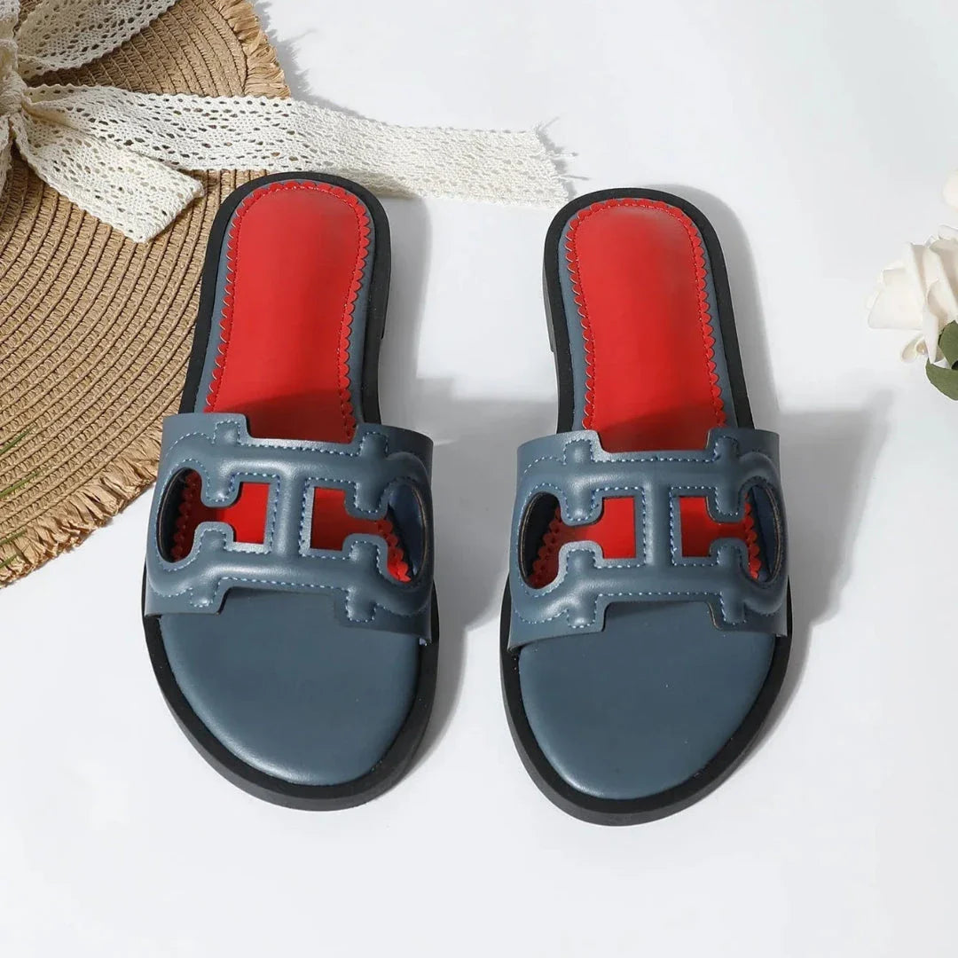 Black cut-out faux leather flat slides with bold red cushioned footbed, open-toe slip-on style