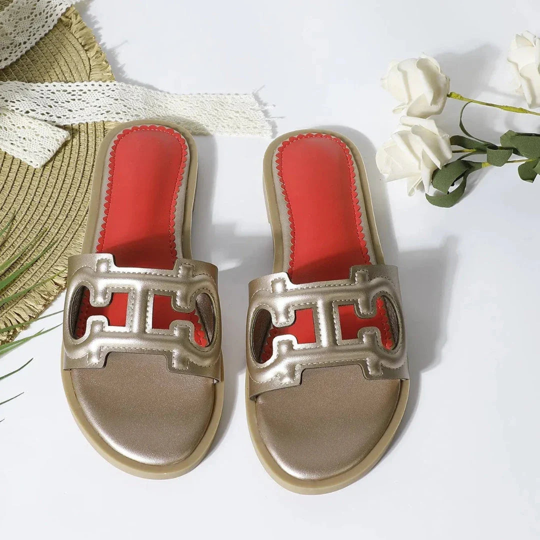 Black faux leather cut-out slides with bold open-toe strap and vibrant red cushioned footbed