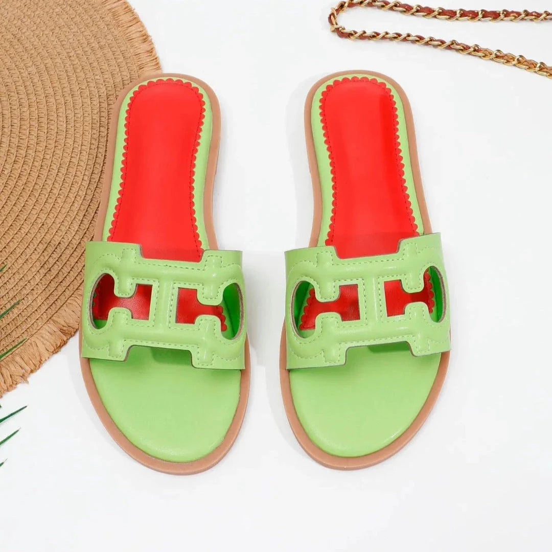 Black cut-out faux leather flat slides with bold red cushioned footbed, open-toe slip-on style