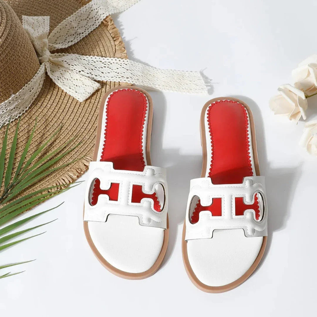 Black cut-out faux leather slides with bold strap design and vibrant red cushioned footbed, flat slip-on