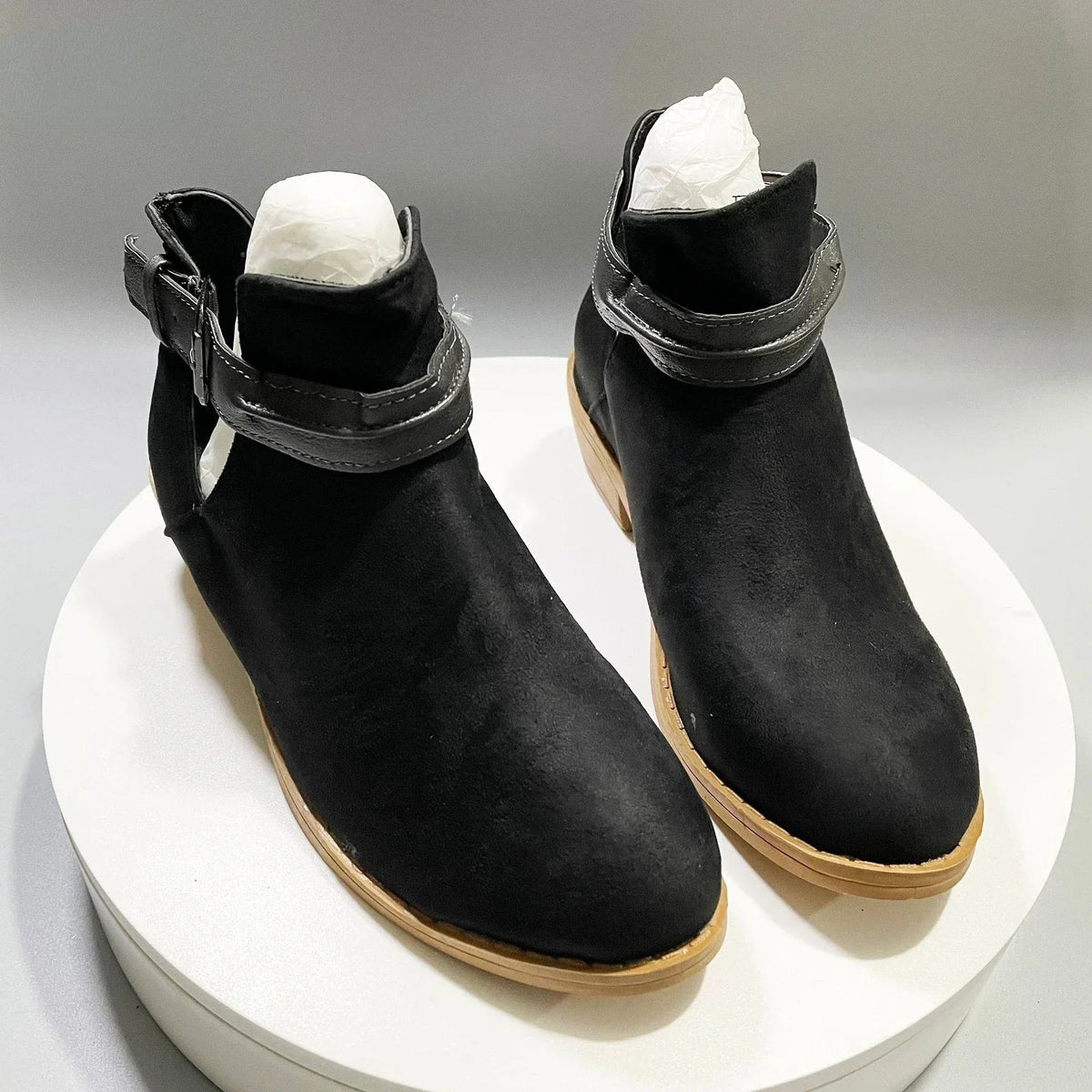 Women's black chic ankle boots with elegant silhouette and adjustable buckle strap detail
