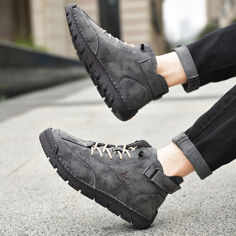 Men's brown vegan leather ankle boots with contrast stitching and adjustable strap, rugged explorer style