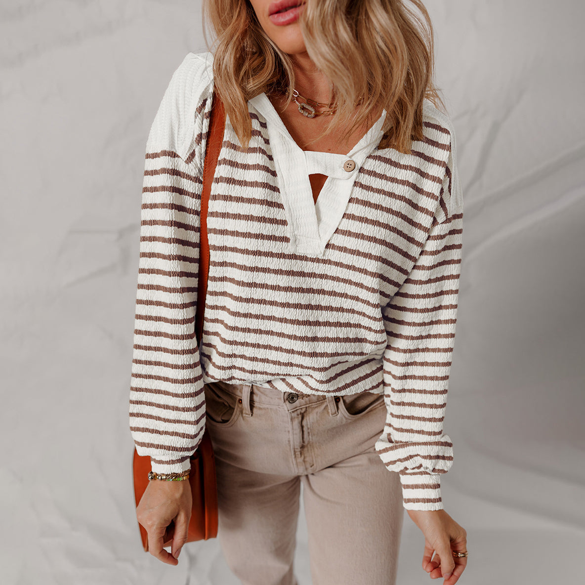 Striped textured V-neck sweater with buttoned strap accent, modern relaxed fit casual style