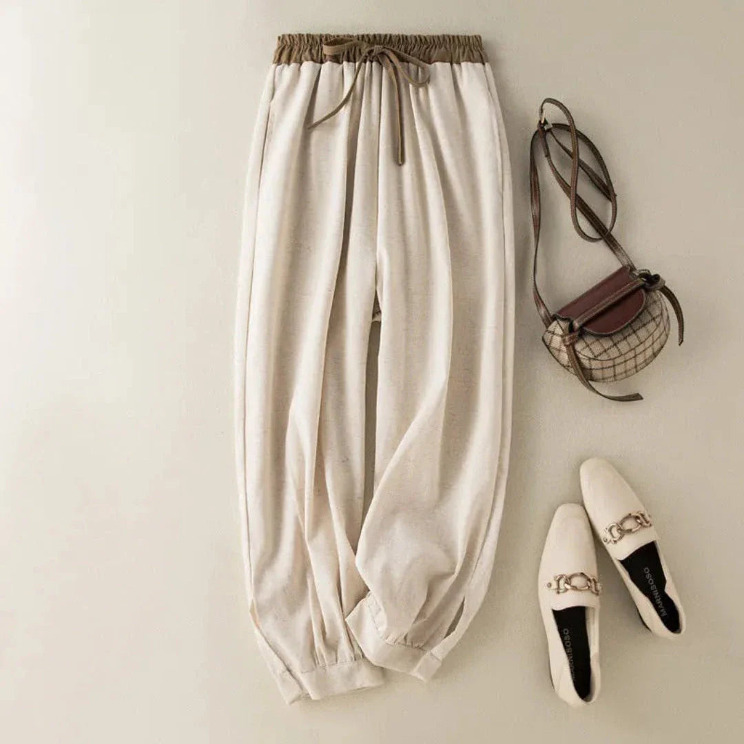 Women's white relaxed-fit linen trousers with drawstring waistband and adjustable cuffed ankles