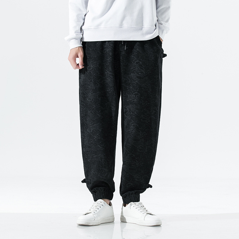 Black tapered joggers with subtle tonal texture, elastic toggle cuffs, and relaxed street-ready fit
