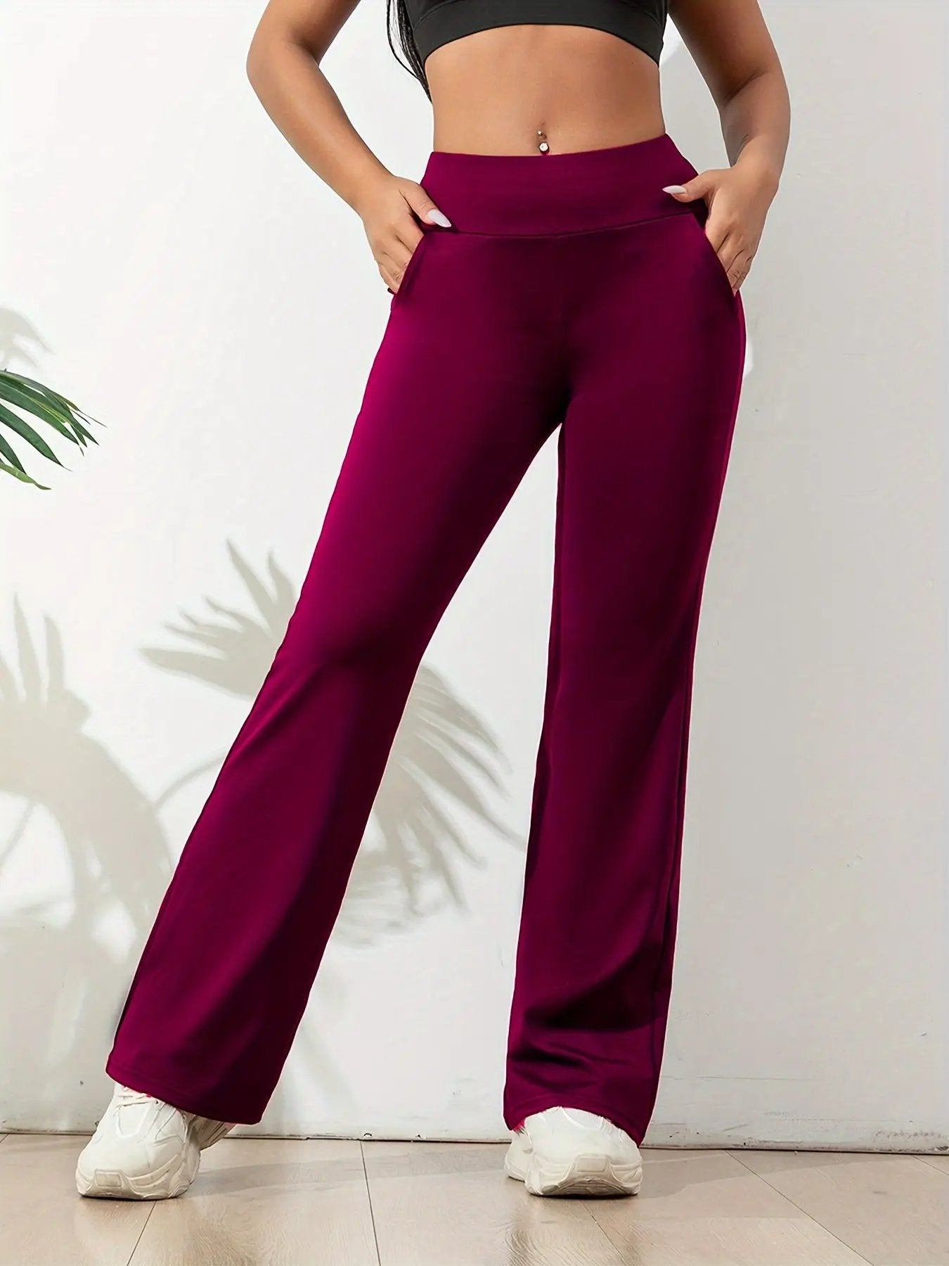 Women's black high-waisted yoga pants with wide waistband, streamlined fit, and side pockets