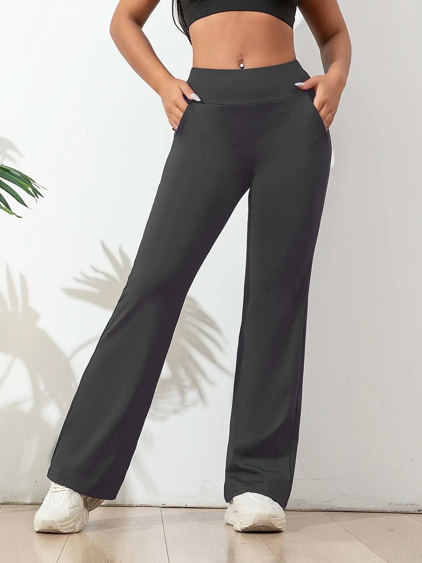 Women's black high-waisted yoga pants with wide waistband, streamlined fit, and side pockets