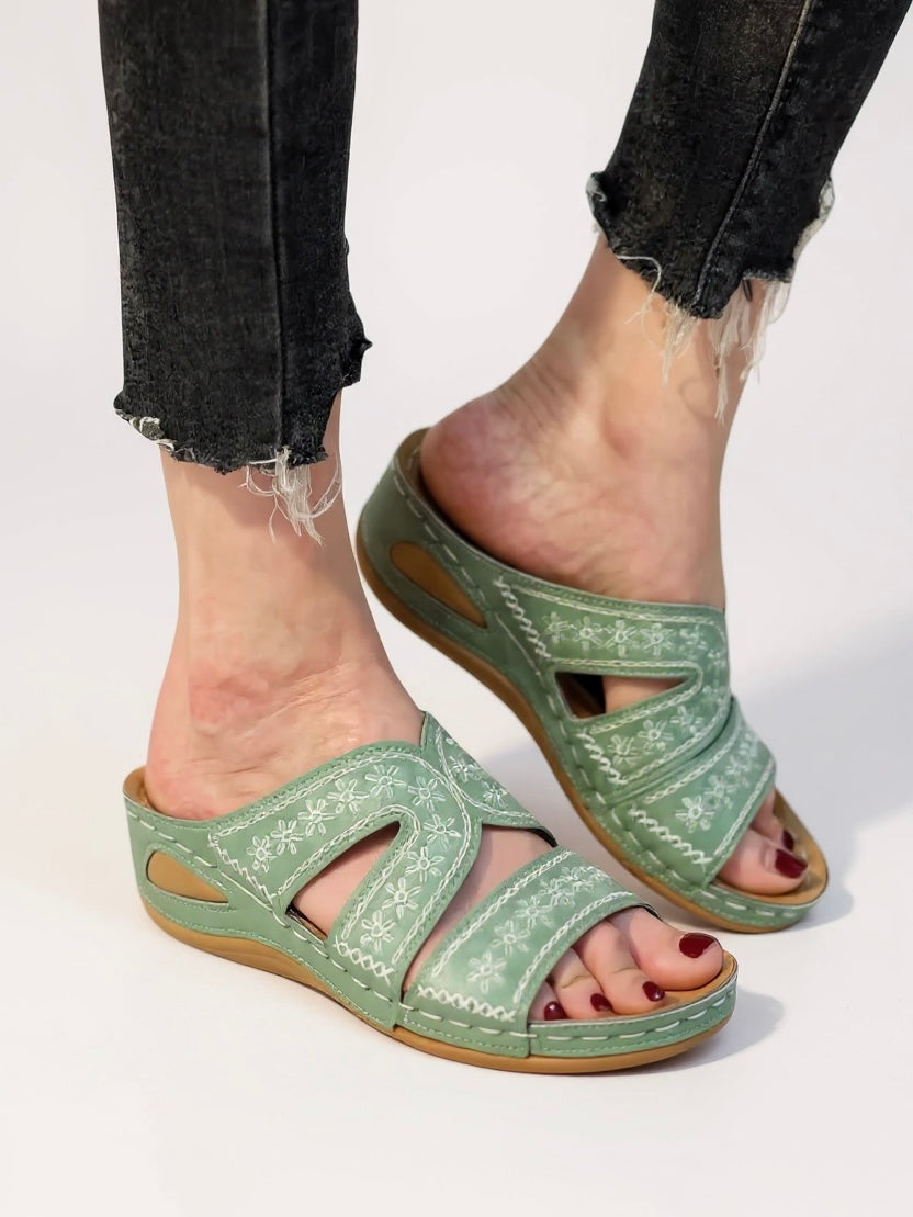 Women's cushioned slip-on sandals in neutral tones with intricate embroidery detail and soft sole