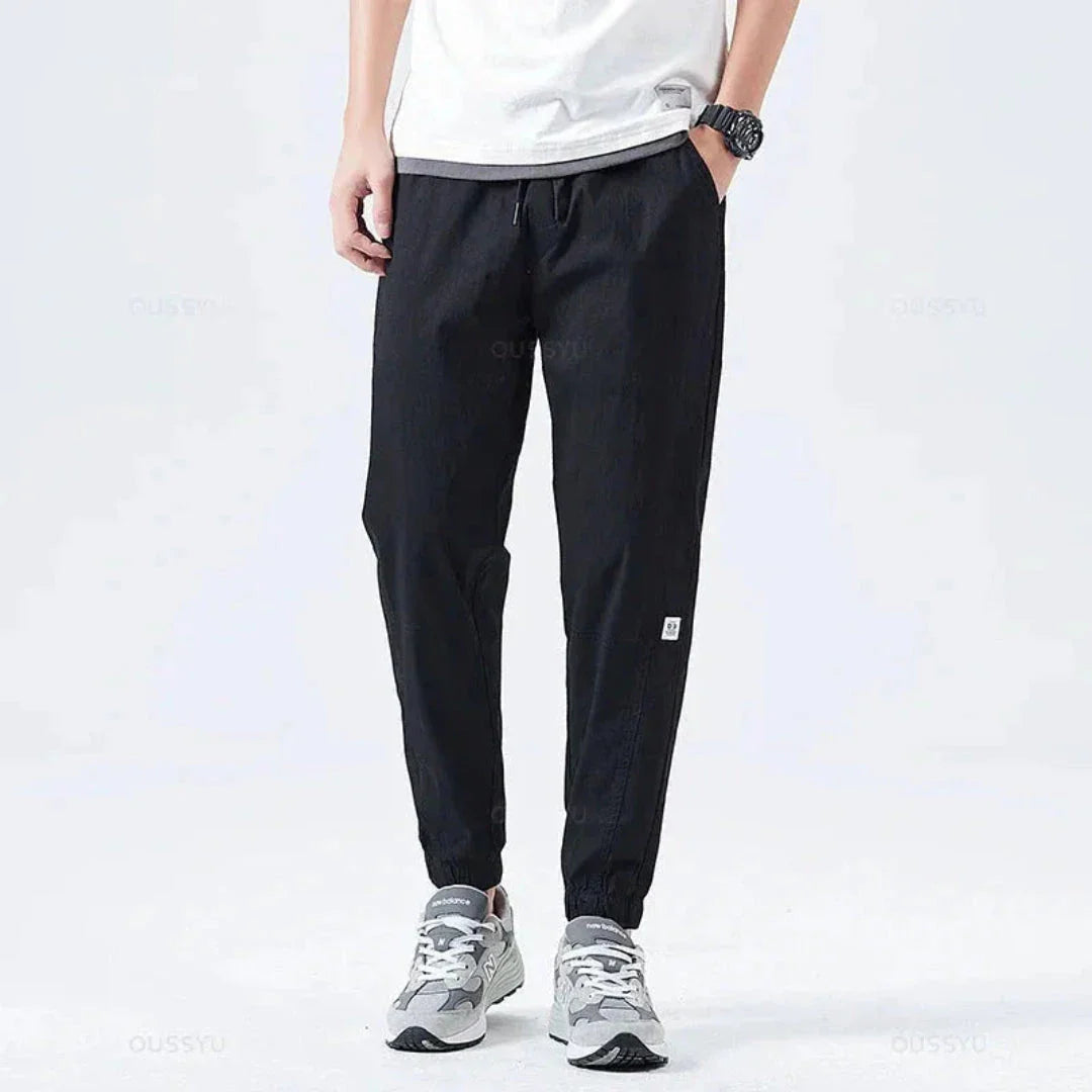 Men's olive green utility cargo jogger pants with multiple functional pockets and drawstring cuffs