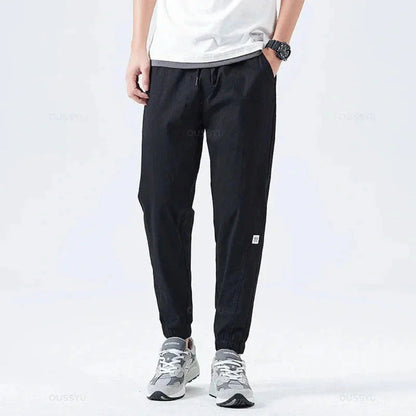 Men's olive green utility cargo jogger pants with multiple functional pockets and drawstring cuffs