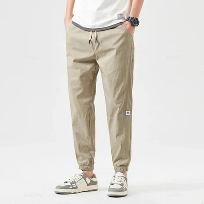 Men's olive green utility cargo jogger pants with multiple functional pockets and drawstring cuffs