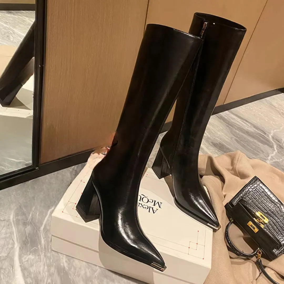 Black glossy leather knee-high boots with sculpted square heel and structured calf-hugging shaft