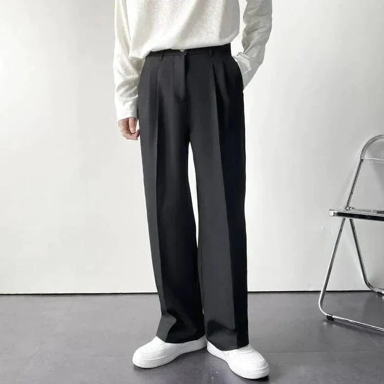 Matt wide-leg pants in neutral tone with tailored pleat detail and flowing minimalist silhouette