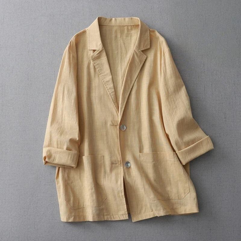 Beige relaxed linen jacket with dropped shoulders, rolled sleeves, and oversized patch pockets