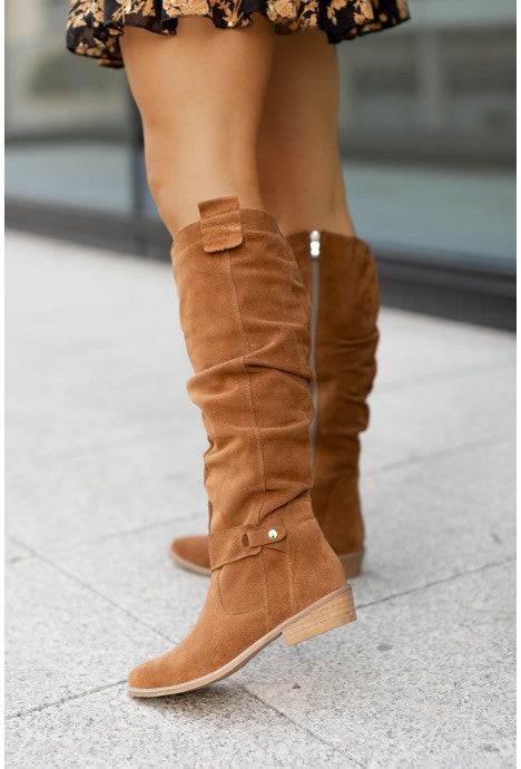 Women's knee-high loose-fit suede boots with flat sole, low heel, side zipper, and decorative buckles