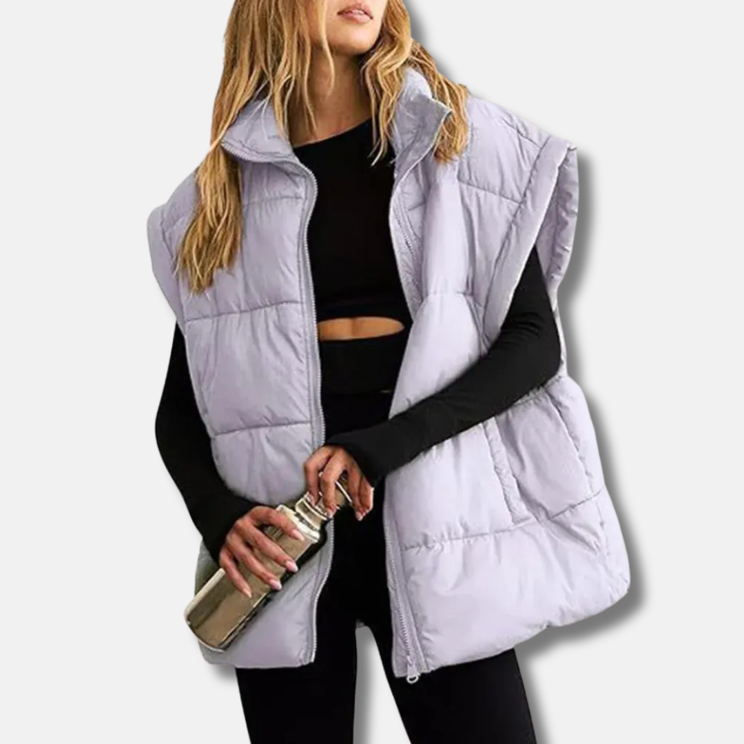 Women's quilted puffer vest in neutral tone, hip-length silhouette with stand collar for sleek layering