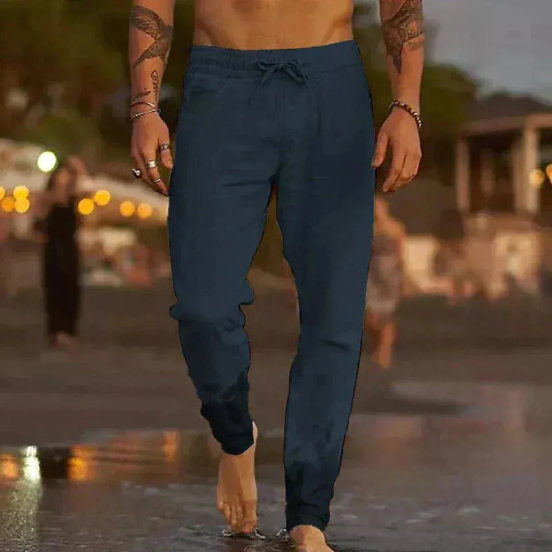 Beige tapered linen pants with elastic waistband and adjustable drawstring for relaxed beach style