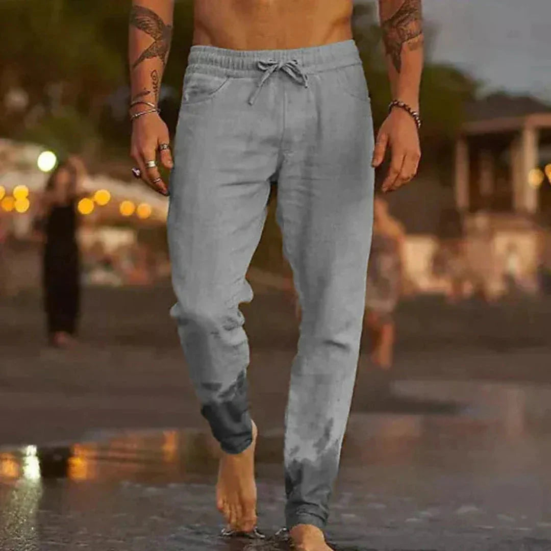 Beige tapered linen pants with elastic waistband and adjustable drawstring for relaxed beach style