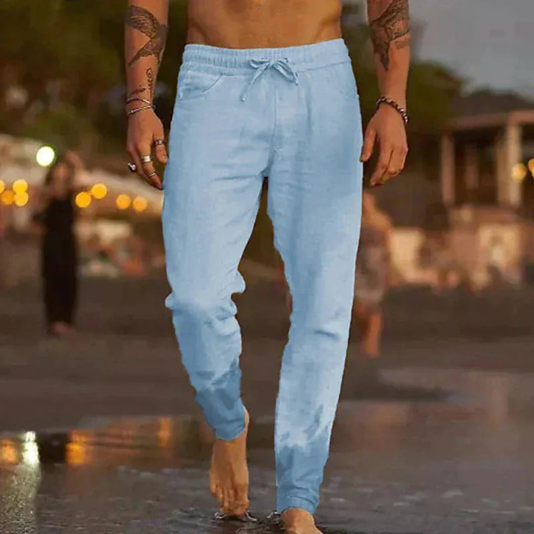 Beige tapered linen pants with elastic waistband and adjustable drawstring for relaxed beach style