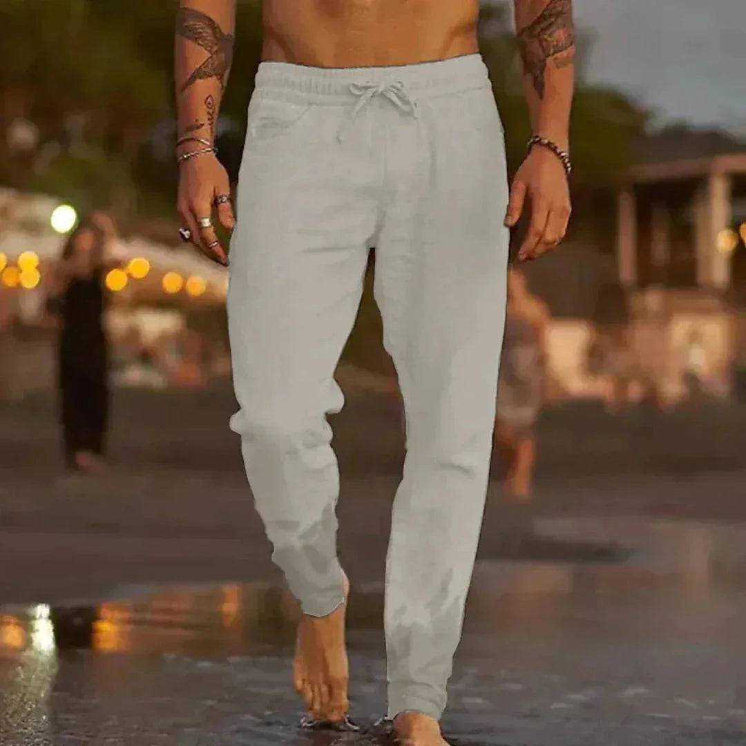 Beige tapered linen pants with elastic waistband and adjustable drawstring for relaxed beach style