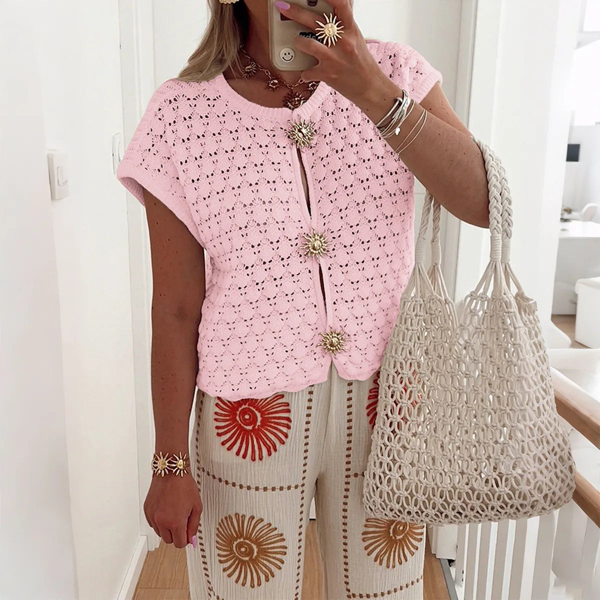 White crochet knit cropped top with floral button accents and relaxed fit for spring