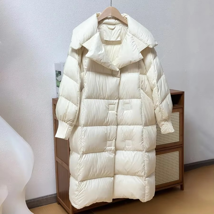 Women's oversized long puffer coat in neutral tone with cozy down filling for winter warmth