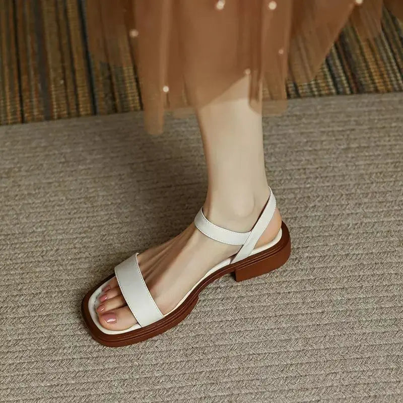 Women's slip-on sandals in neutral tone with cushioned sole and minimalist buckle accent detail