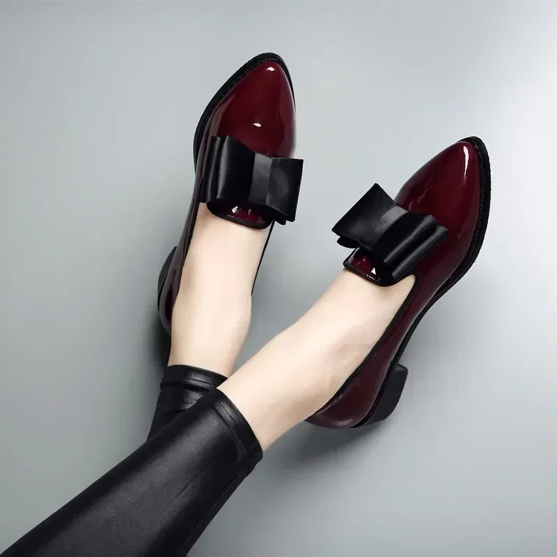 Black patent leather pumps with bold bow tie detail, sleek professional silhouette for women