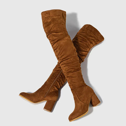 Black over-the-knee heeled boots with block heel, sleek silhouette, bold statement fashion style