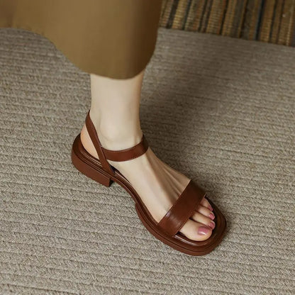Women's slip-on sandals in neutral tone with cushioned sole and minimalist buckle accent detail