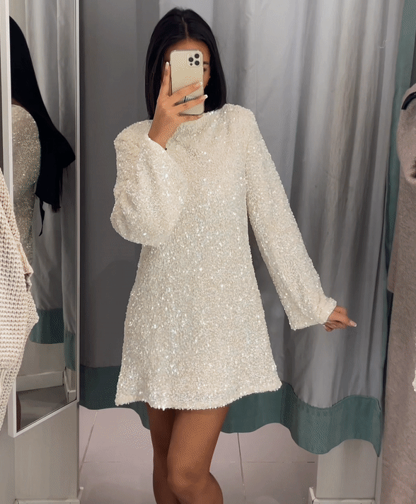 Women's silver sequin mini dress with long sleeves, open back, and statement bow detail