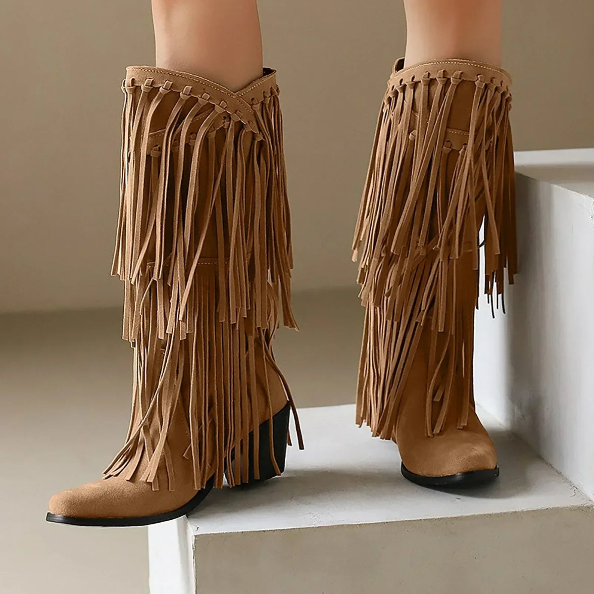 Women's tan western knee-high boots with long flowing fringe detailing and sturdy block heel