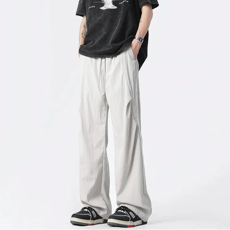 Neutral tufted parachute pants wide-leg relaxed fit with chrome-tip drawstrings and crinkled nylon fabric