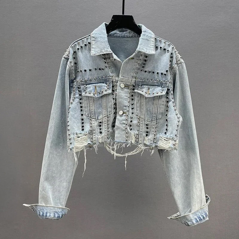 Cropped blue distressed denim jacket with metallic stud embellishments and structured fit