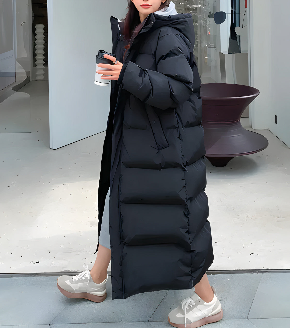 Women's long black puffer jacket with hooded design, insulated snap placket, and sleek winter silhouette