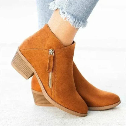 Women's tan suede ankle boots with low block heel, side zip closure, and sleek streamlined silhouette