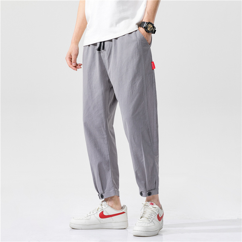 Tapered cropped linen trousers relaxed tailored fit with minimalist design and discreet red tag accent